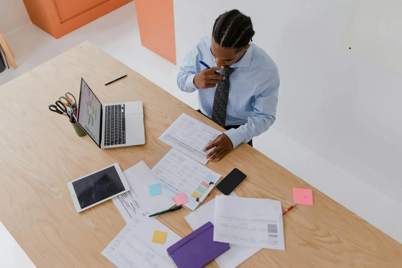 Entrepreneur rédigeant son business plan sur un ordinateur portable, documents et tableaux financiers posés sur le bureau