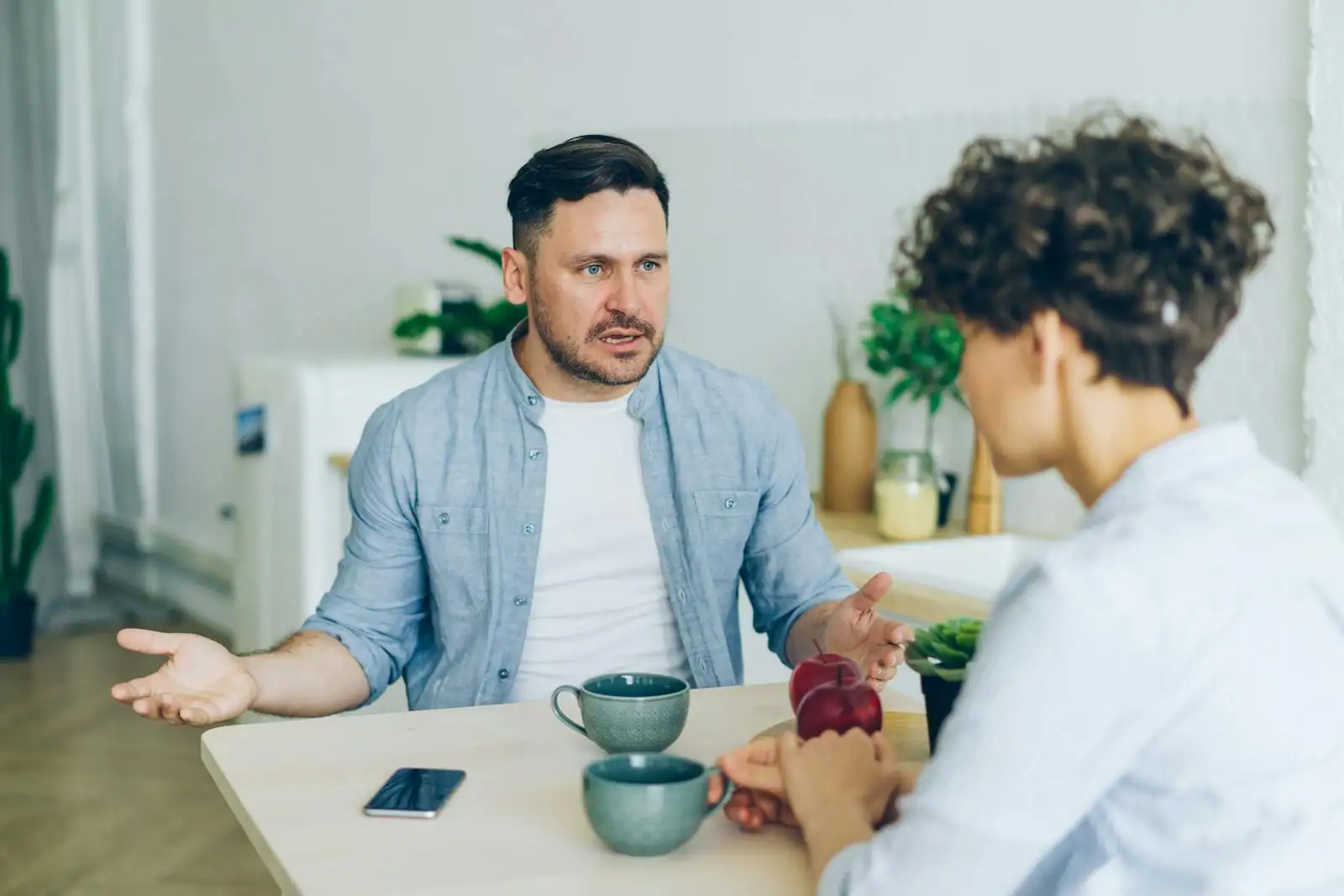 Deux personnes en conversation calme à une table, écoute attentive et posture détendue
