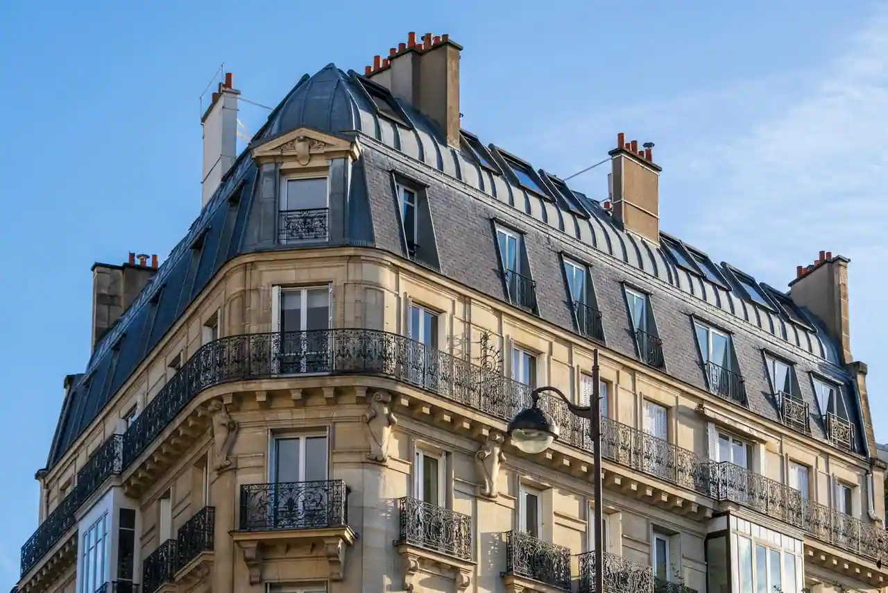 Immeuble haussmannien parisien aux façades en pierre claire vu en perspective sur une avenue arborée