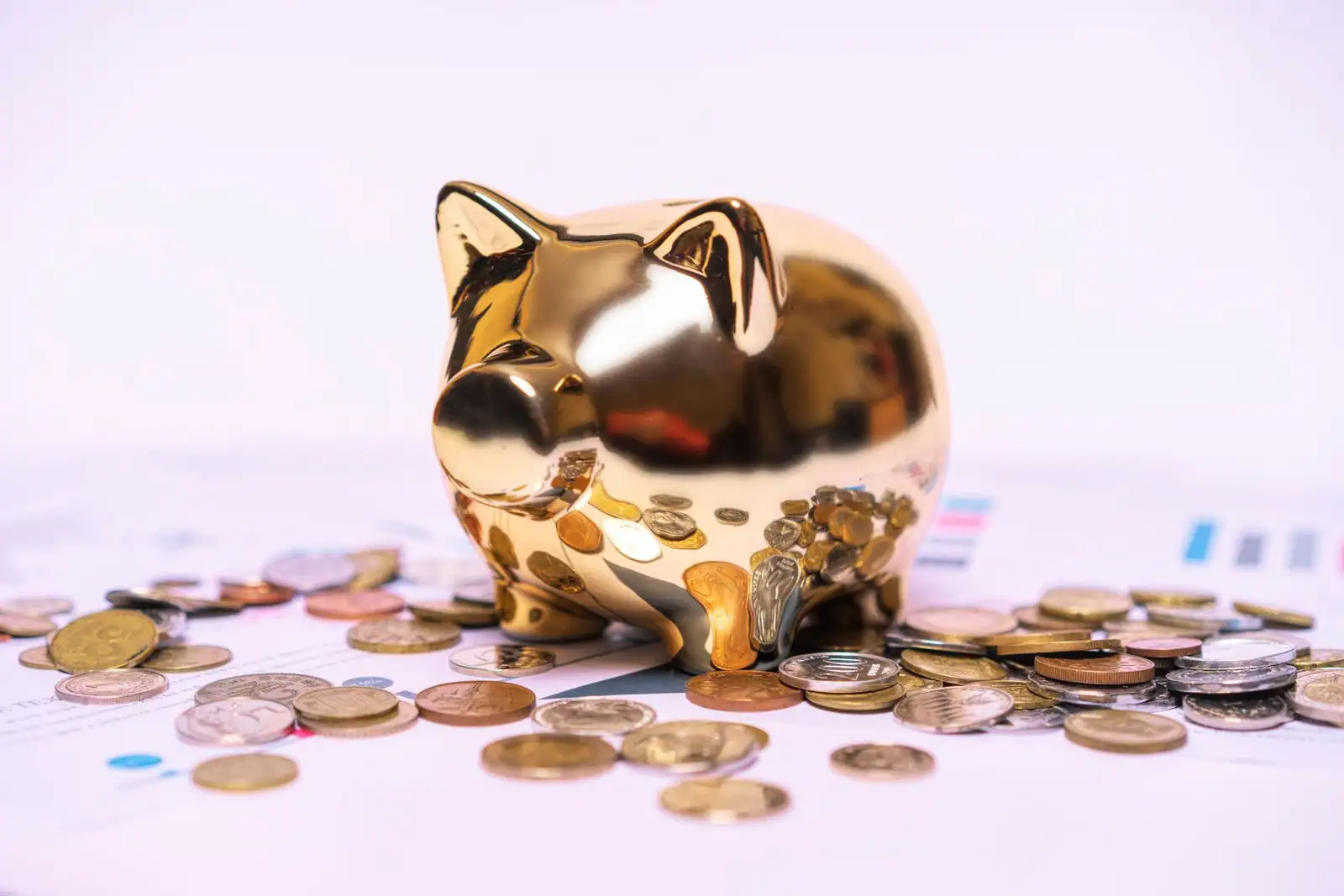 Tirelire et pièces d'épargne posées à côté d'un relevé bancaire et d'une calculatrice