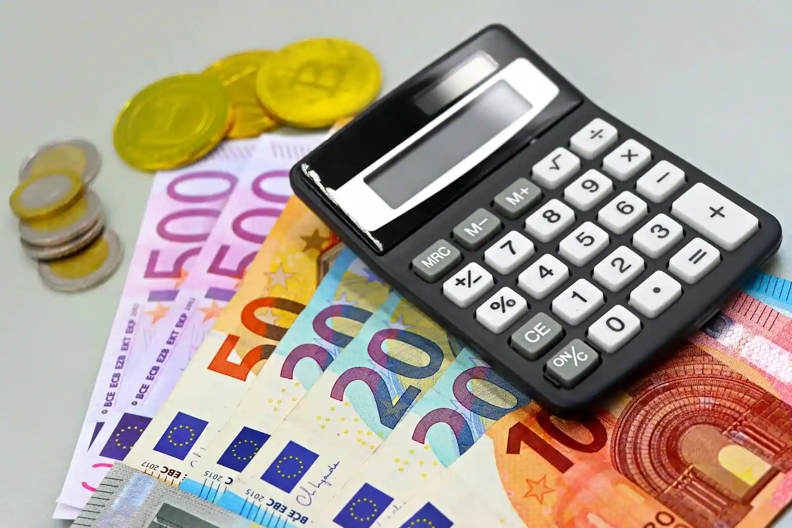 Pièces et billets en euros posés près d'une calculatrice, illustrant l'épargne et les placements.