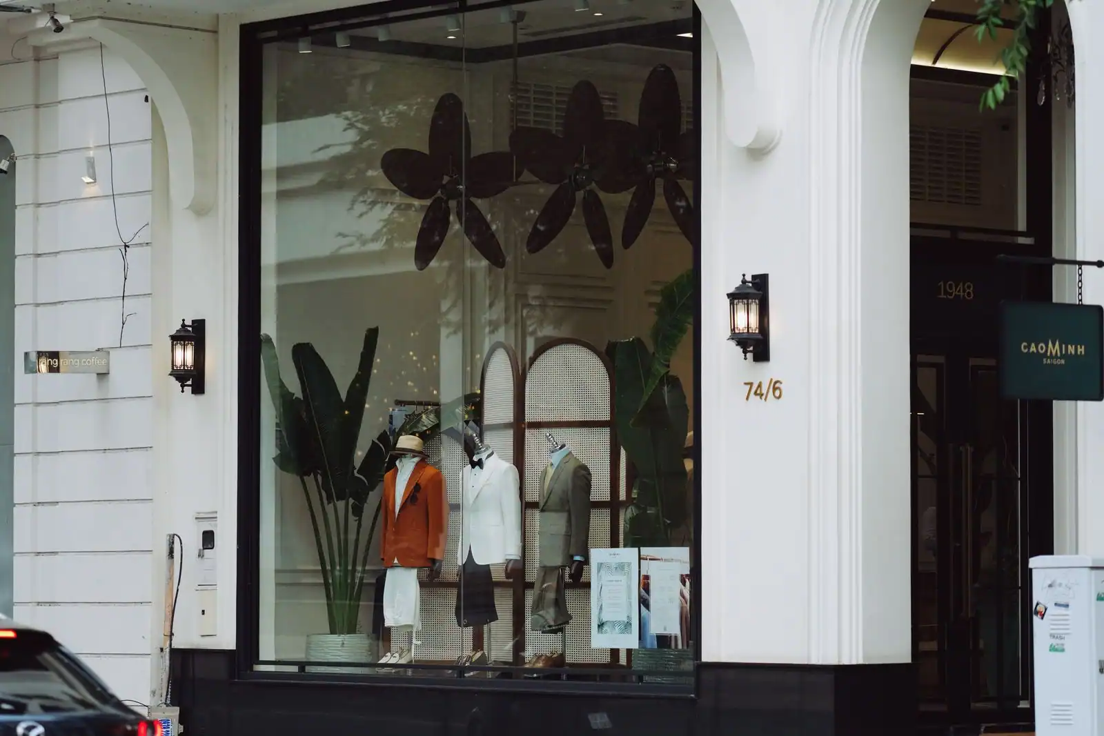 Vitrine élégante d'une boutique de mode, mannequins en costume derrière une grande verrière.