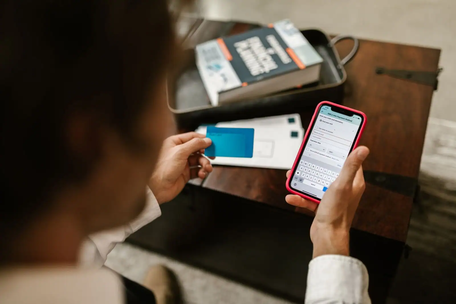 Personne utilisant une application bancaire sur son smartphone, une carte bancaire à la main