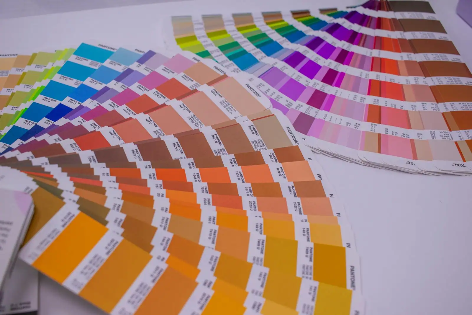 Nuanciers de couleurs déployés en éventail sur un plan de travail, outil de communication visuelle