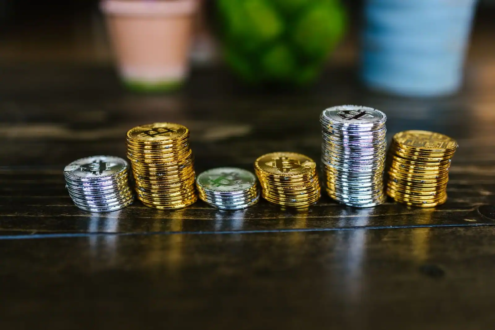 Piles de pièces physiques de cryptomonnaie sur une table en bois, évoquant l'investissement en bitcoin