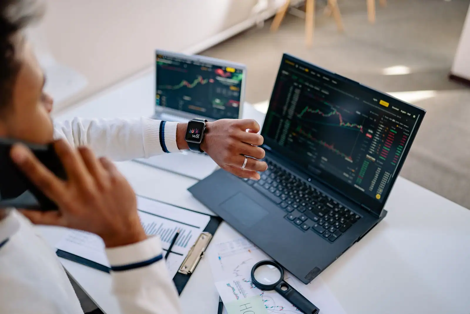 Personne analysant des courbes et graphiques de données sur deux ordinateurs portables à un bureau
