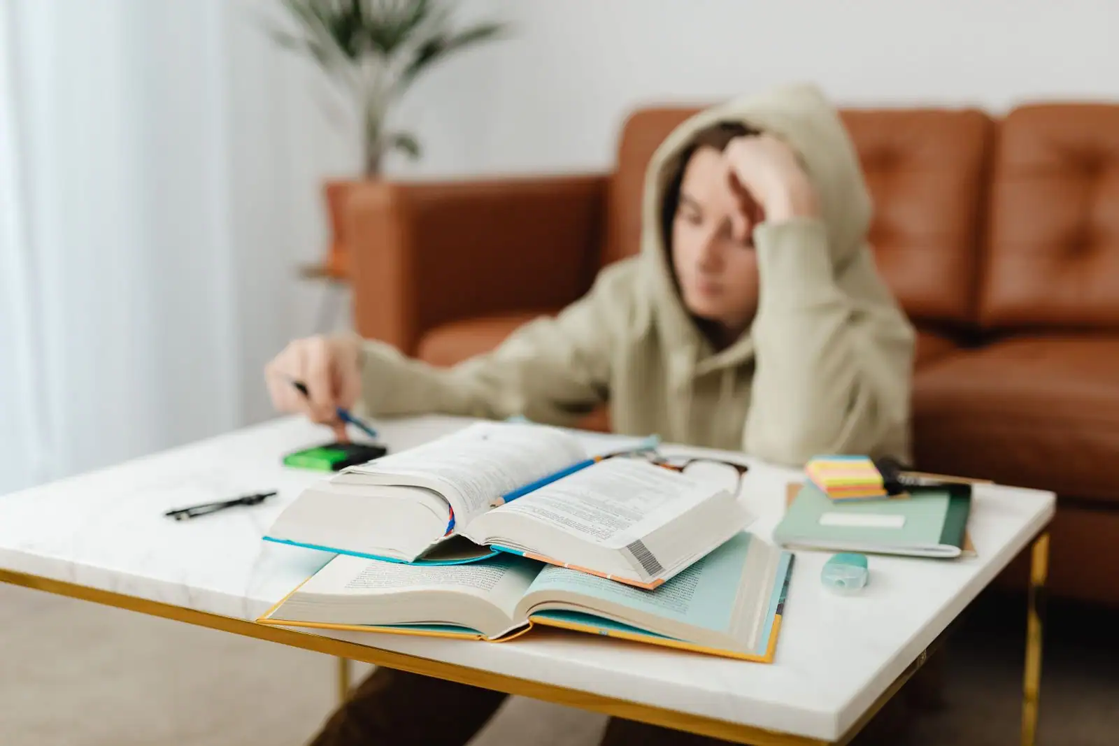 Un lycéen révise à une table basse, entouré de livres et de cahiers ouverts.