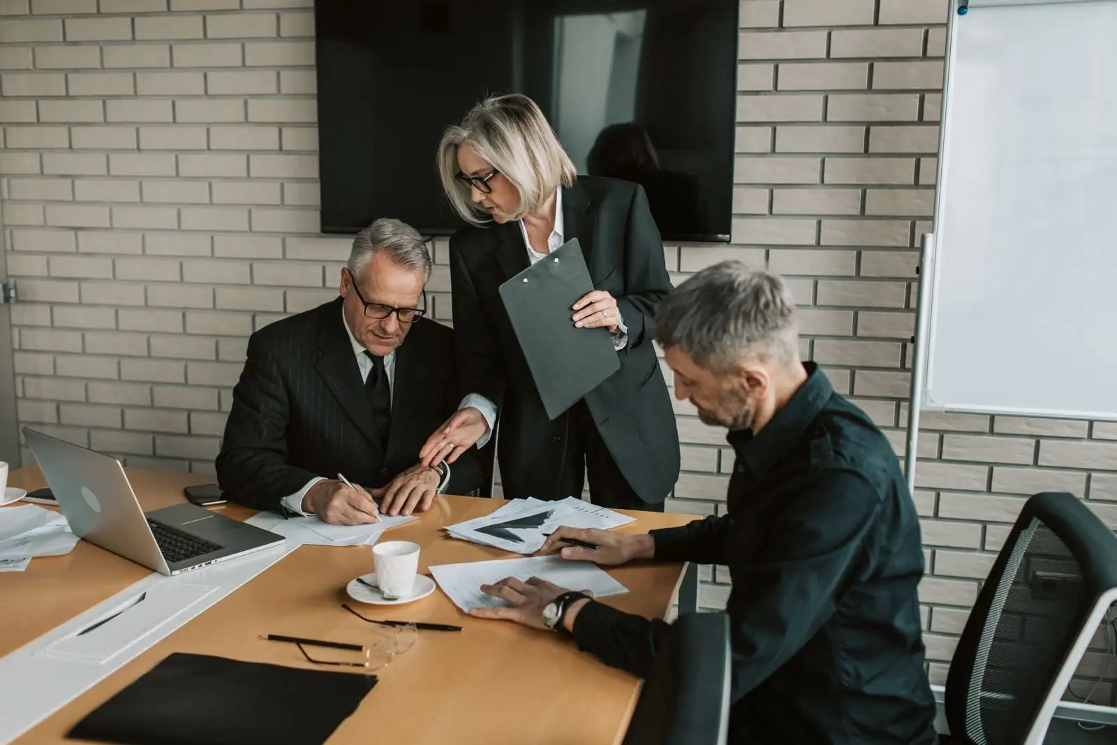 Trois professionnels réunis autour d’une table de travail dans une salle de réunion