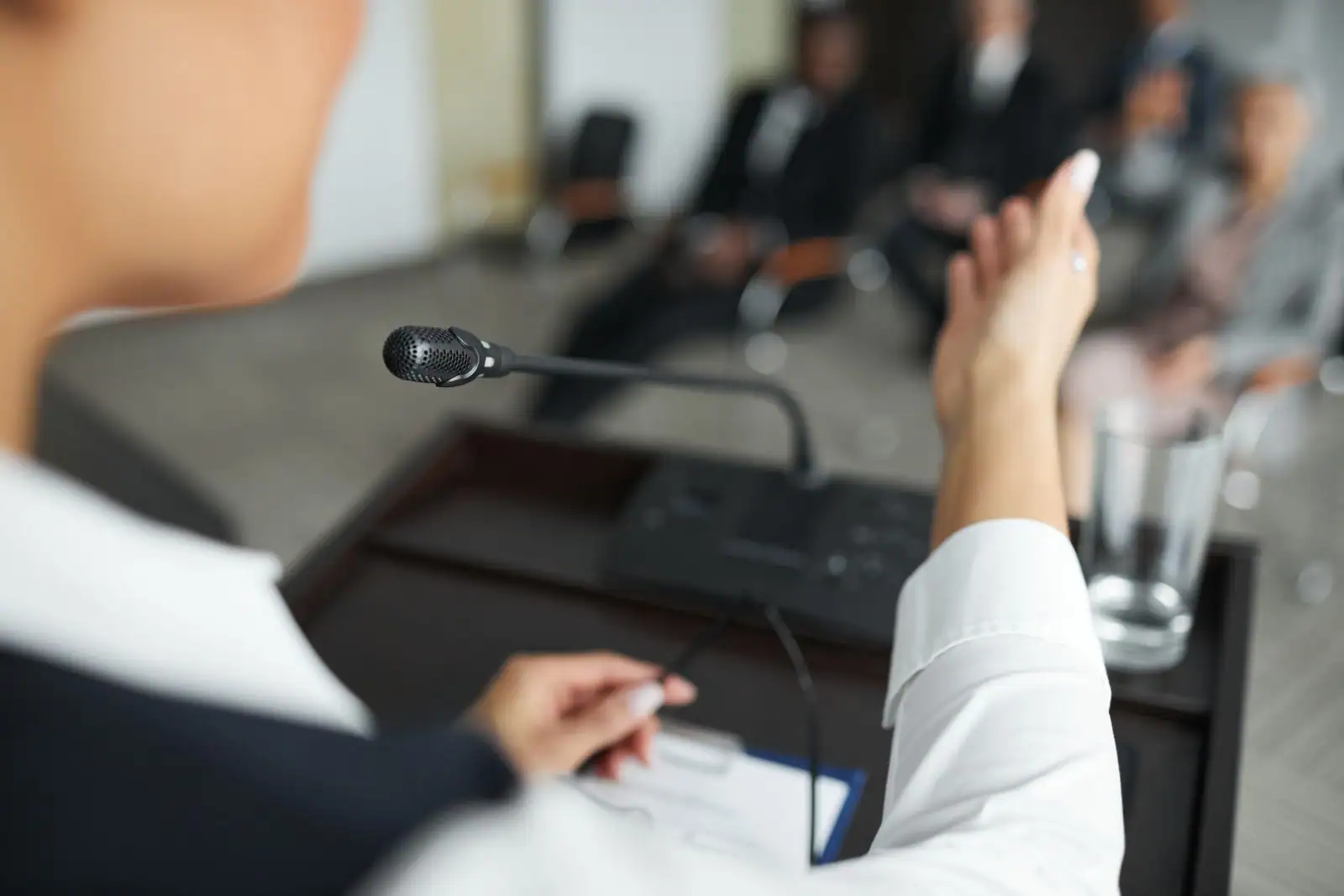 Une intervenante s'adresse à un auditoire au micro, lors d'une réunion d'information.