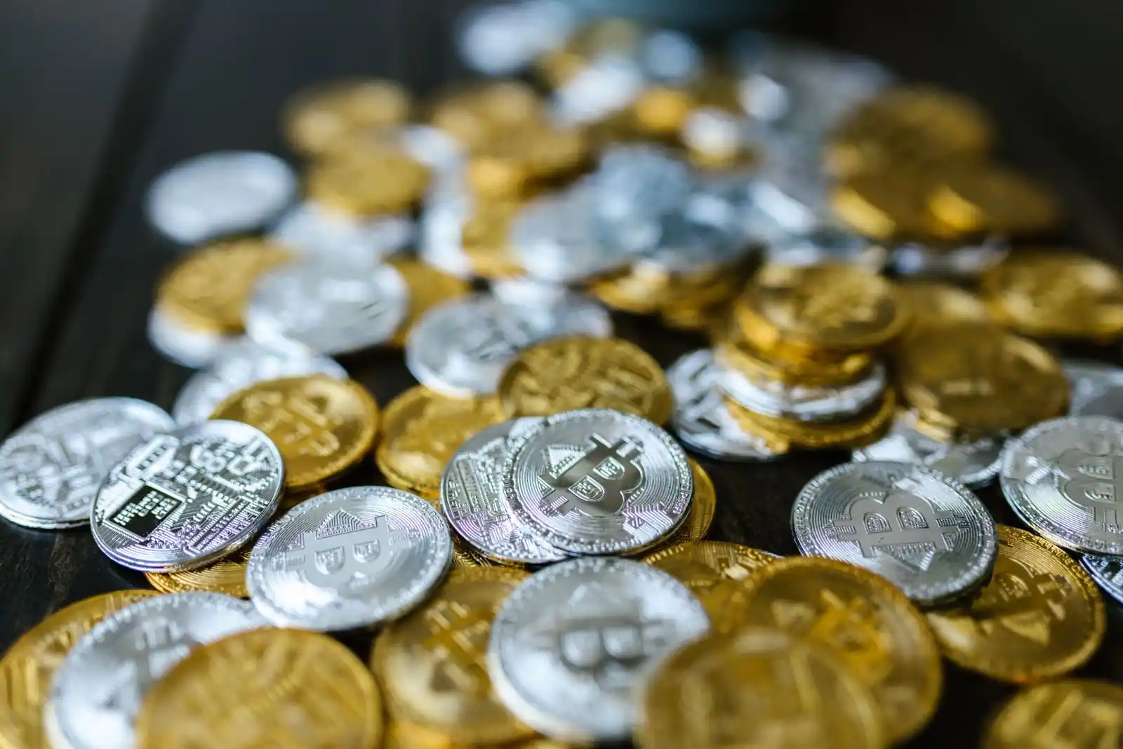 Pièces physiques dorées et argentées frappées du symbole bitcoin, illustrant les crypto monnaies