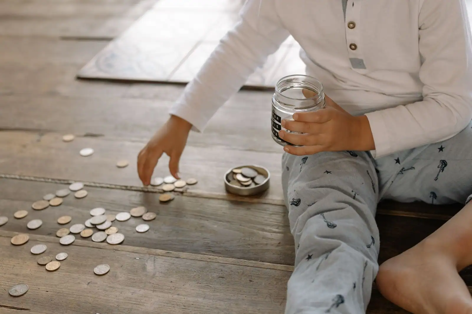 Des pièces de monnaie rassemblées près d'un bocal en verre, sur le thème de l'épargne.