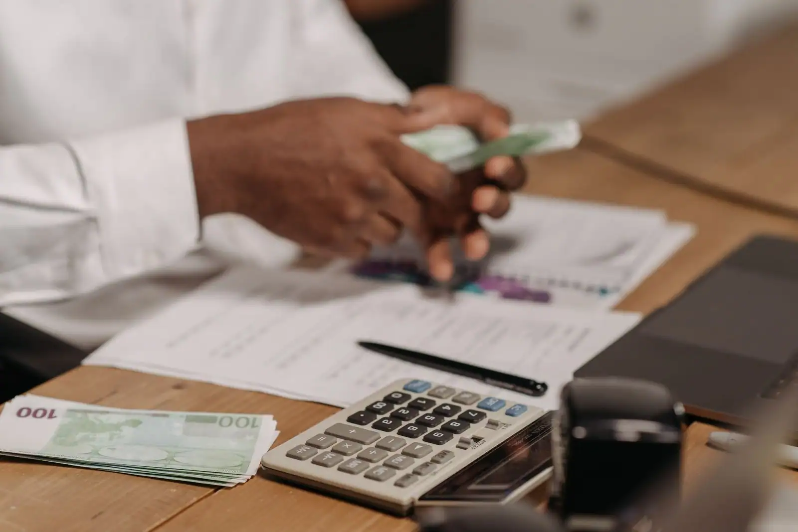 Billets en euros, calculatrice et documents financiers posés sur un bureau