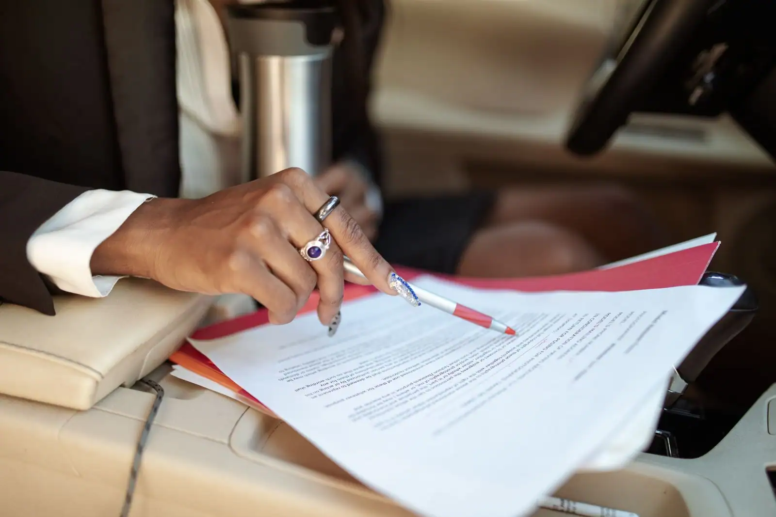 Personne en tenue professionnelle annotant un contrat imprimé, stylo rouge à la main