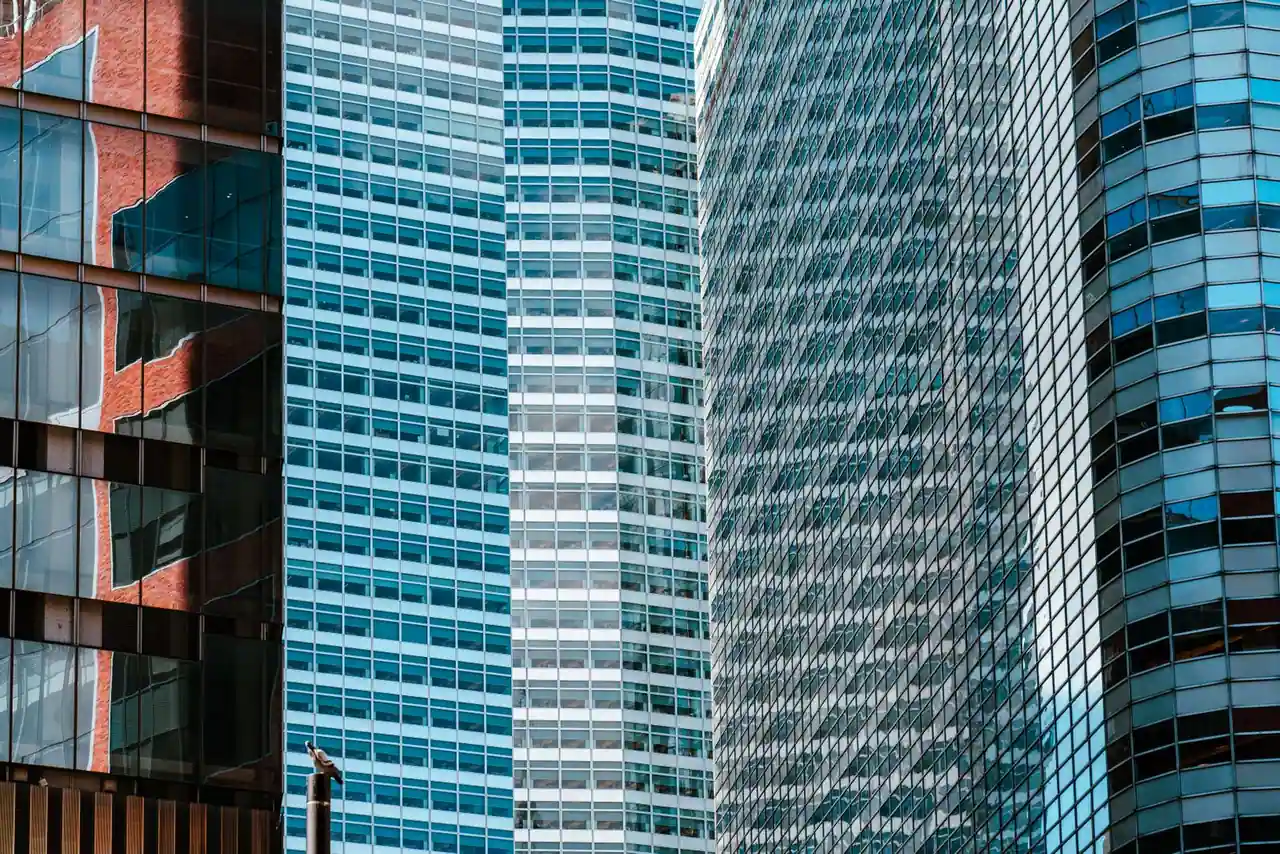 Tours de bureaux vitrées d'un quartier d'affaires moderne, évoquant le secteur de la finance