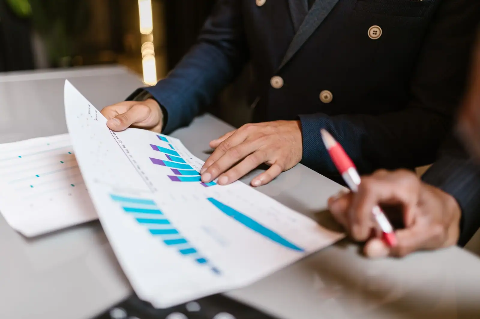 Professionnel examinant des graphiques financiers imprimés lors d'une réunion de gestion de portefeuille