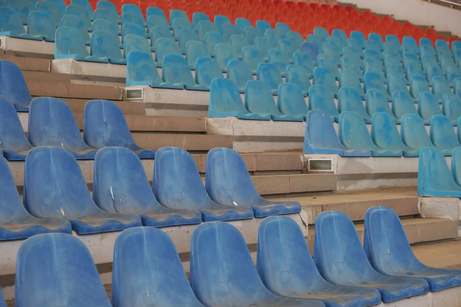 Gradins de sièges vides bleus et orange dans une enceinte sportive