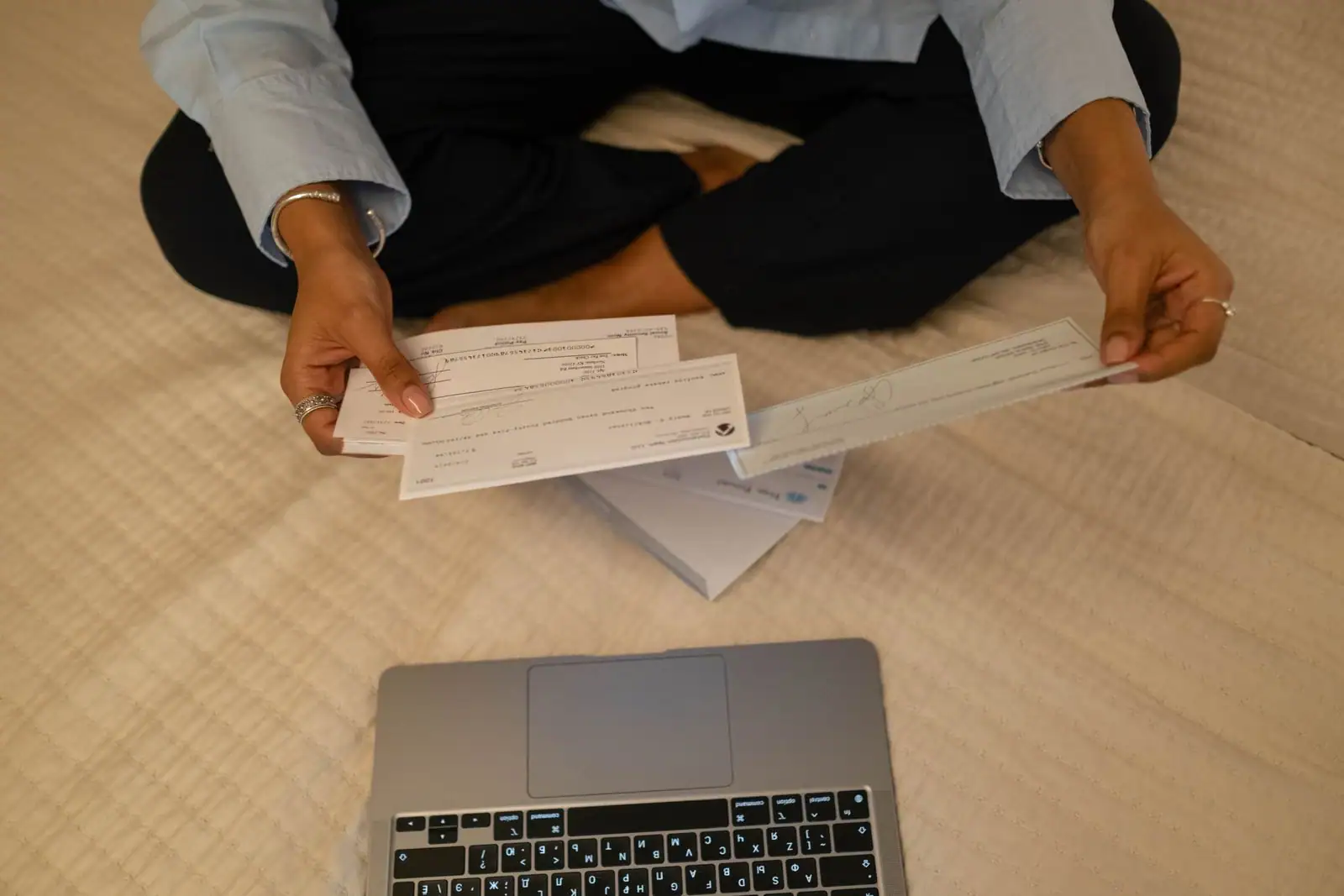 Personne tenant des documents financiers devant un ordinateur portable, illustration de démarches en ligne