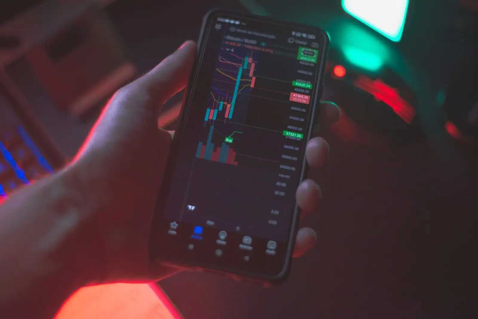 Une main tient un smartphone affichant une application de cryptomonnaies avec un graphique de cours.