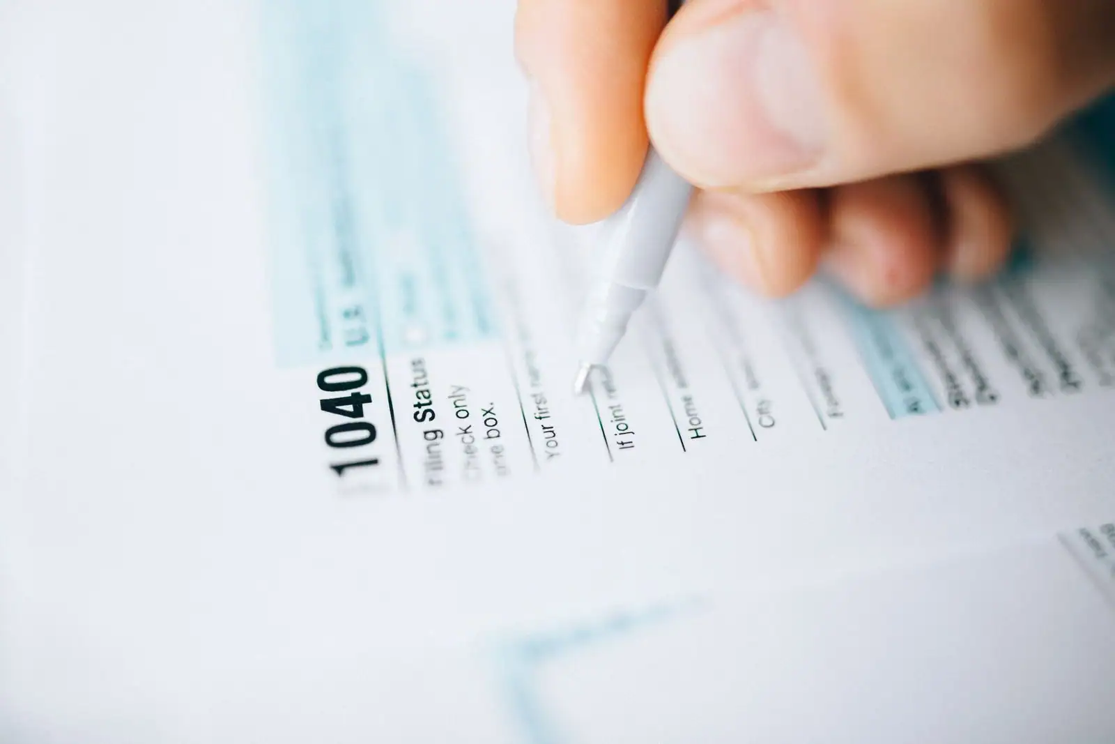 Gros plan d'une main remplissant au stylo un formulaire de déclaration fiscale.