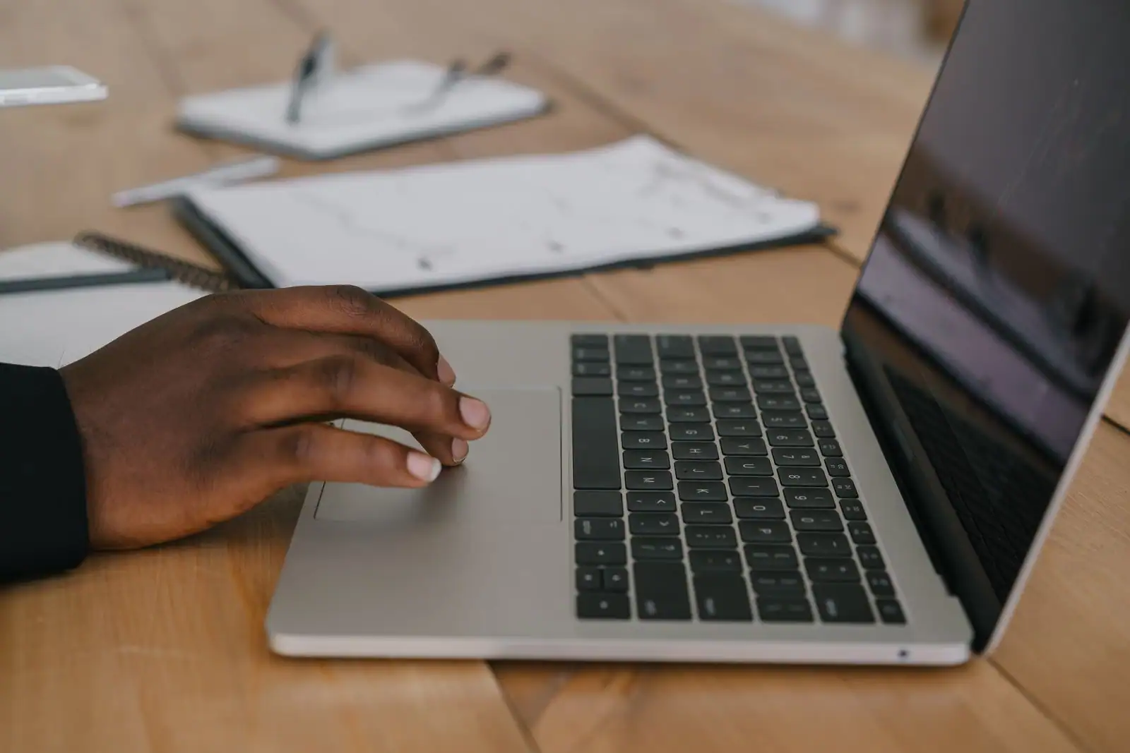 Une personne utilise un ordinateur portable à un bureau clair, illustrant une recherche d'emploi en ligne.