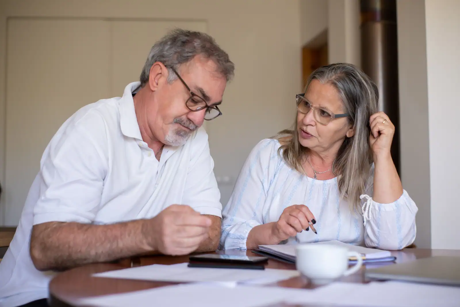 Couple de seniors examinant ensemble des documents financiers et prenant des notes à leur table