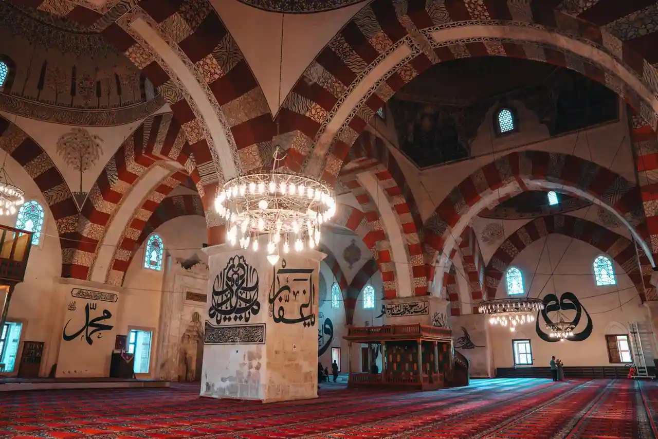 Intérieur d'une mosquée aux arches rayées et à la calligraphie murale, vaste salle de prière