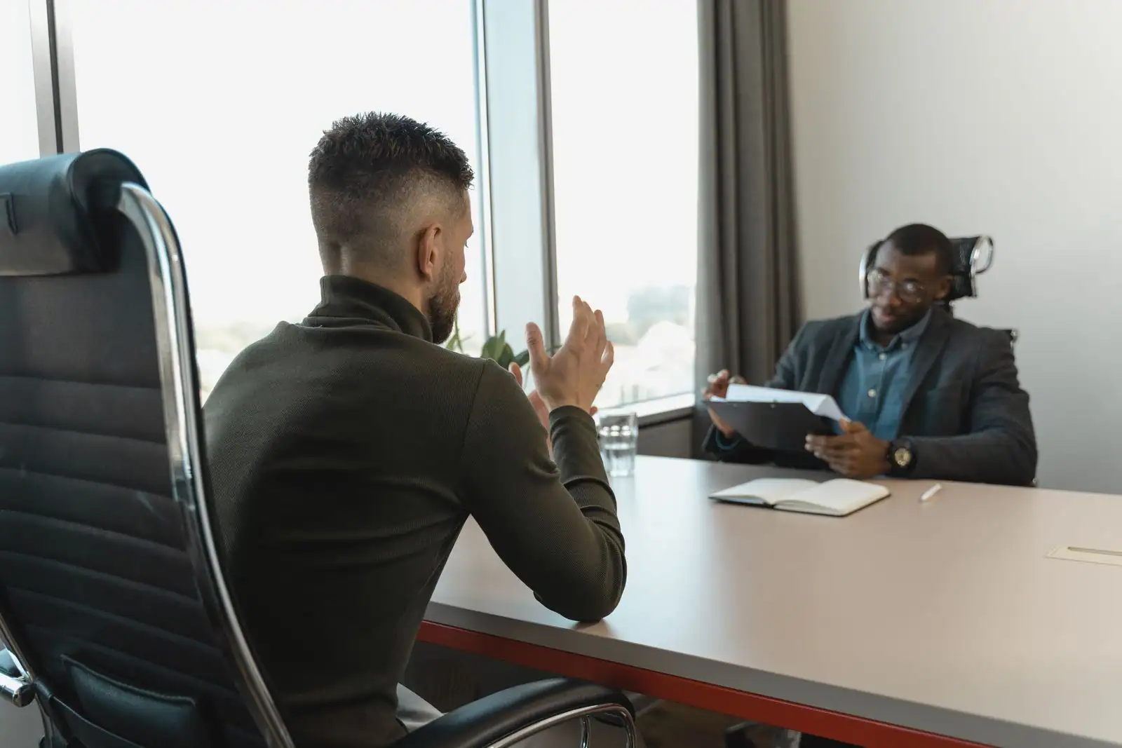 Un entretien d'embauche entre un candidat et un recruteur, assis face à face dans un bureau.