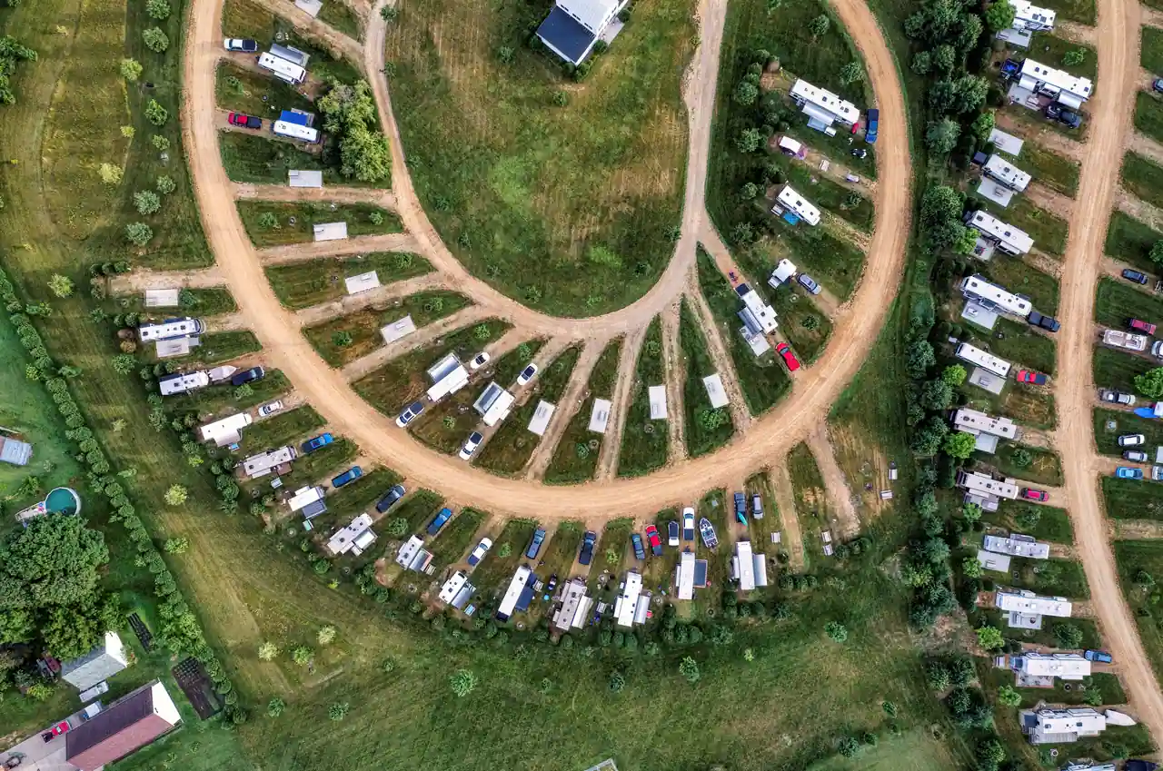 Vue aérienne d'un terrain de camping, emplacements délimités par des haies le long des allées.